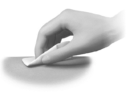 A hand gently applying an adhesive patch or dressing onto a flat and light surface