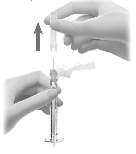 A hand lifting a transparent protective cap from a needle attached to a medical syringe indicated by an arrow pointing upward