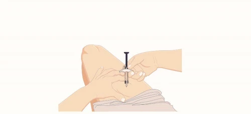 A hand holding a syringe with needle pointing downward while the