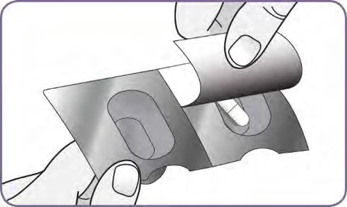 Two hands lifting the aluminum foil of a blister pack to remove a white capsule from its silver metallic cavity