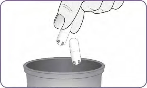 A hand holding a white capsule above an open container while a