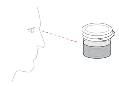 Profilo di un volto umano con una linea tratteggiata rossa che indica l'uso di un contenitore trasparente con coperchio bianco per l'applicazione nasale