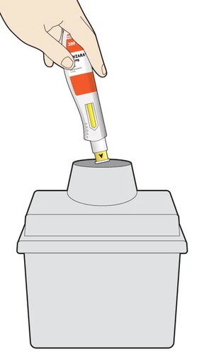 A hand holds a white and orange autoinjector with yellow tip and inserts it into the top of a gray container for disposal