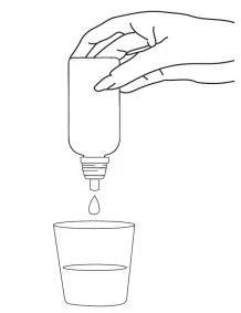 A hand holds an inverted bottle to dispense a drop of liquid into a glass filled with water