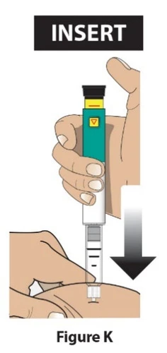 Una mano tiene verticalmente un dispositivo medico di colore verde e bianco per inserirlo nella pelle seguendo la direzione di una freccia nera
