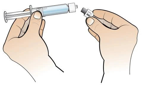 Two hands preparing a syringe with blue liquid by bringing the protective cap close to the tip