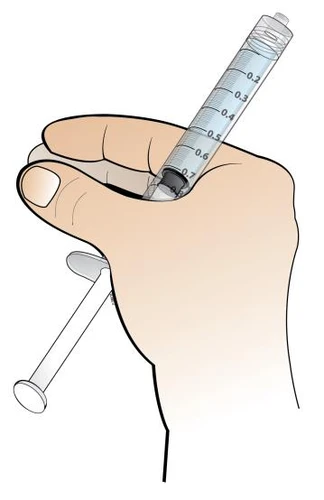A hand holds a transparent syringe with milliliter graduations and a white plunger for administration