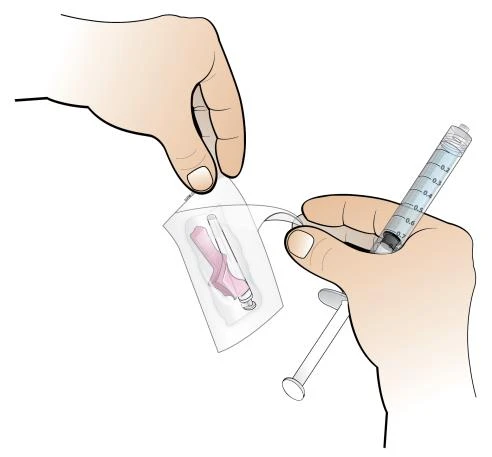 A hand holds a transparent pouch containing a pink vial while another hand prepares the medication