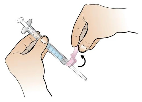 Two hands hold a syringe with blue liquid while one hand rotates a pink cap onto the tip