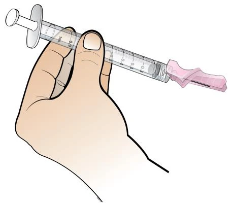A hand holds a transparent syringe with milliliter graduations and a pink cap on the tip for administration