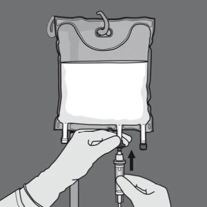 Gloved hands using a syringe to withdraw liquid from an infusion bag hanging on a stand