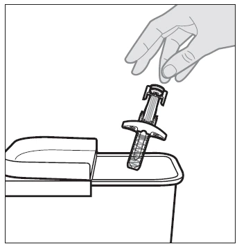 Una mano tiene un dispositivo medico a forma di siringa sopra l'apertura di un contenitore per lo smaltimento dei rifiuti sanitari