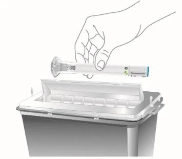 A hand holding an injection pen horizontally ready to be inserted into a sharps waste disposal container