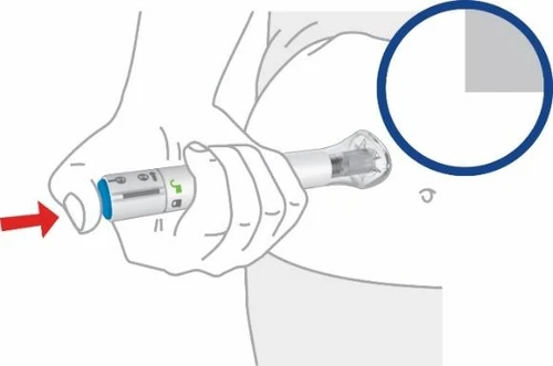 A hand holding a white and gray injection pen placed on the