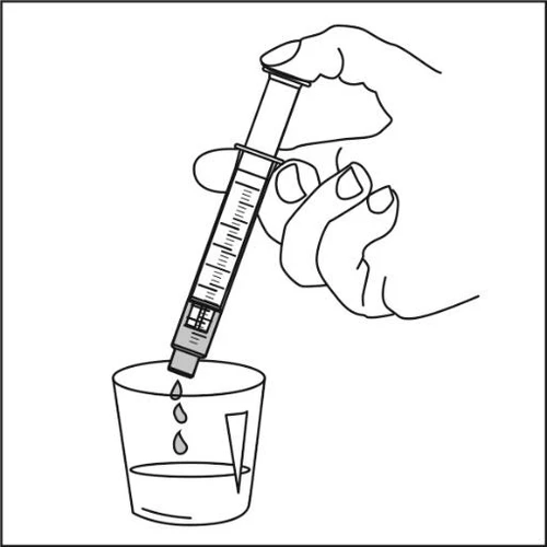 Una mano tiene una siringa graduata sopra un bicchiere di vetro da cui cadono due gocce di liquido