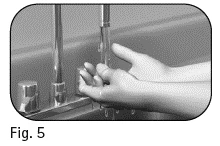 Two hands hold a vertical syringe with needle and glass vial next to a cylindrical container on a flat surface