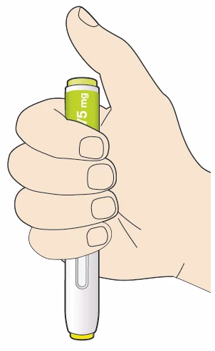 A hand holding vertically a white injection pen with a green upper section displaying the text 5 mg