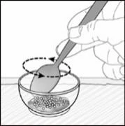 A hand uses a spoon to stir a granular substance in a circular motion