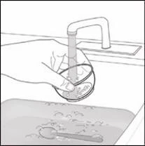 A hand holds a bowl under an open tap while water flows into it