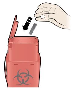 A hand inserting a used needle into a red biological waste container marked with the biohazard symbol