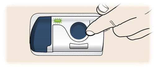 A hand pressing a finger against the blue circular button of a white medical device with a green light on and a dark side section