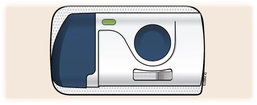 White medical device with a dark blue section on the left, a green button on top, and a large blue circle on the right