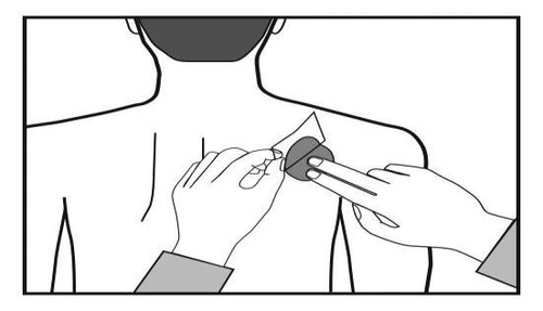 Two hands applying an adhesive patch to the upper back of a person viewed from behind