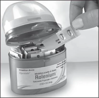 Una mano estrae una dose di polvere inalatoria dal contenitore cilindrico del dispositivo Elpenhaler Rolenium con etichetta informativa