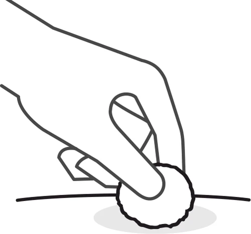 Una mano tiene un dischetto di cotone bianco e lo preme delicatamente su una piccola ferita o zona della pelle con un cerchio grigio chiaro