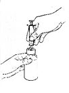A hand holds a syringe to aspirate liquid from a vial held steady by another hand.