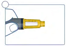 A hand holds a yellow and gray medical device with a transparent container for the medication