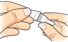 Due mani tengono e separano un dispositivo medico bianco composto da due parti cilindriche connettibili tra loro