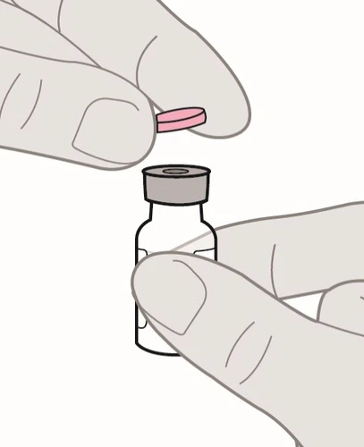 Due mani tengono una piccola pillola rosa sopra il tappo grigio di un flaconcino di vetro trasparente per la preparazione del farmaco