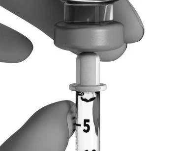 A hand holds a medical dropper with a graduated scale showing the number 5 on a white background