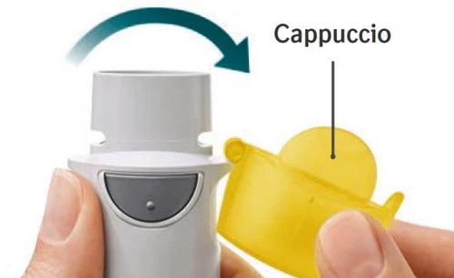 Hands removing a yellow cap from a white medical device with a curved arrow indicating clockwise rotation