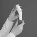 Due mani tengono verticalmente una penna iniettiva medica bianca e cilindrica su uno sfondo grigio uniforme