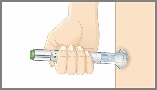Una mano impugna orizzontalmente un dispositivo medico cilindrico bianco e trasparente premendolo contro la pelle di una gamba o un braccio