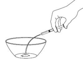 A hand holding a syringe with a long needle drawing liquid from a transparent bowl placed on a flat surface