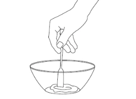 A hand holding a stirring stick mixing a creamy substance in a container