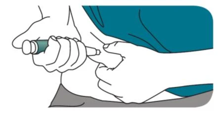 Two hands holding an injection pen to apply it to the skin of the thigh or abdomen