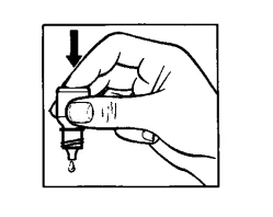 A hand holds an inverted bottle from which a drop of liquid is falling, with a black arrow pointing downward on the cap