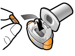 A hand opening the white and gray protective cap of a circular medical device with orange details to reveal the inside