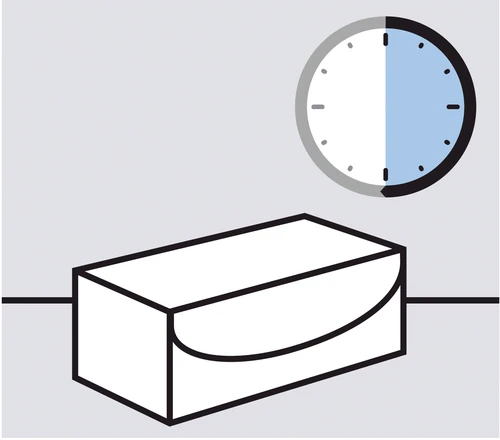 Un reloj analógico con una sección azul entre las 12 y las 6 colocado encima de un contenedor rectangular blanco con tapa en forma de semicírculo
