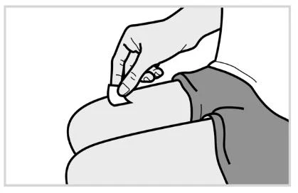 A hand holds a small cotton pad and presses it on the upper thigh of a person for disinfection