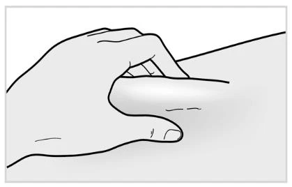 A hand gently pinches a skin fold on a fleshy body surface to prepare the area for