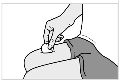 A hand holds a cotton pad and presses it on the upper thigh of a seated person