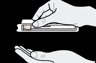 Two hands handling a rectangular white medical device with an orange part on a black background