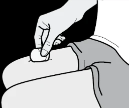 Una mano preme un dischetto di cotone bianco sulla pelle della coscia di una persona che indossa indumenti grigi