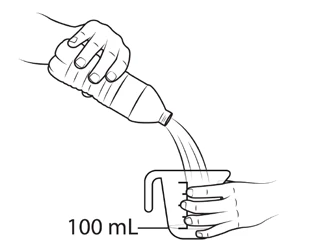 A hand pours the contents of a bottle into a graduated cylinder held by a hand