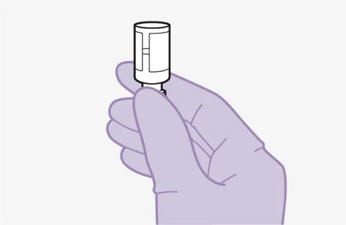 A lilac-colored gloved hand firmly holding a white cylindrical vial with a small protrusion at the base